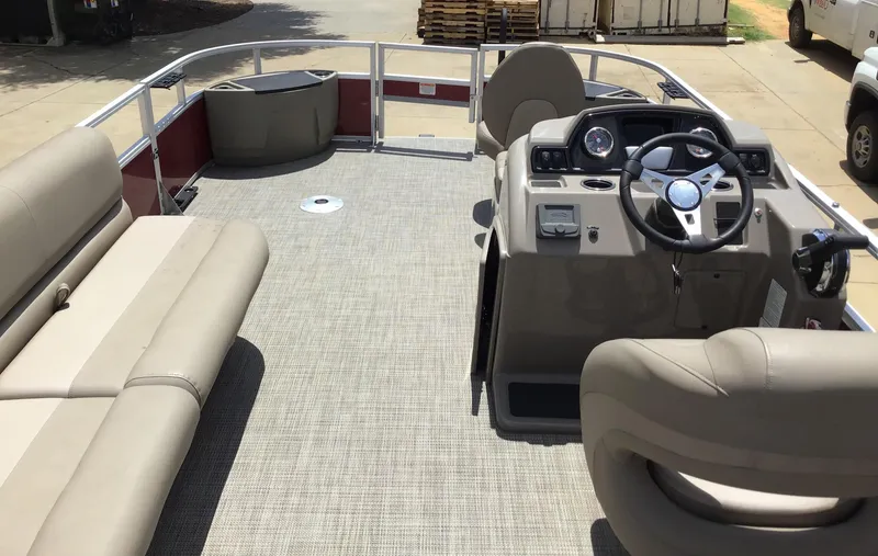 Slide: The Image of 2024 Ranger Reata 200F pontoon boat interior with beige seating and steering console. - 2
