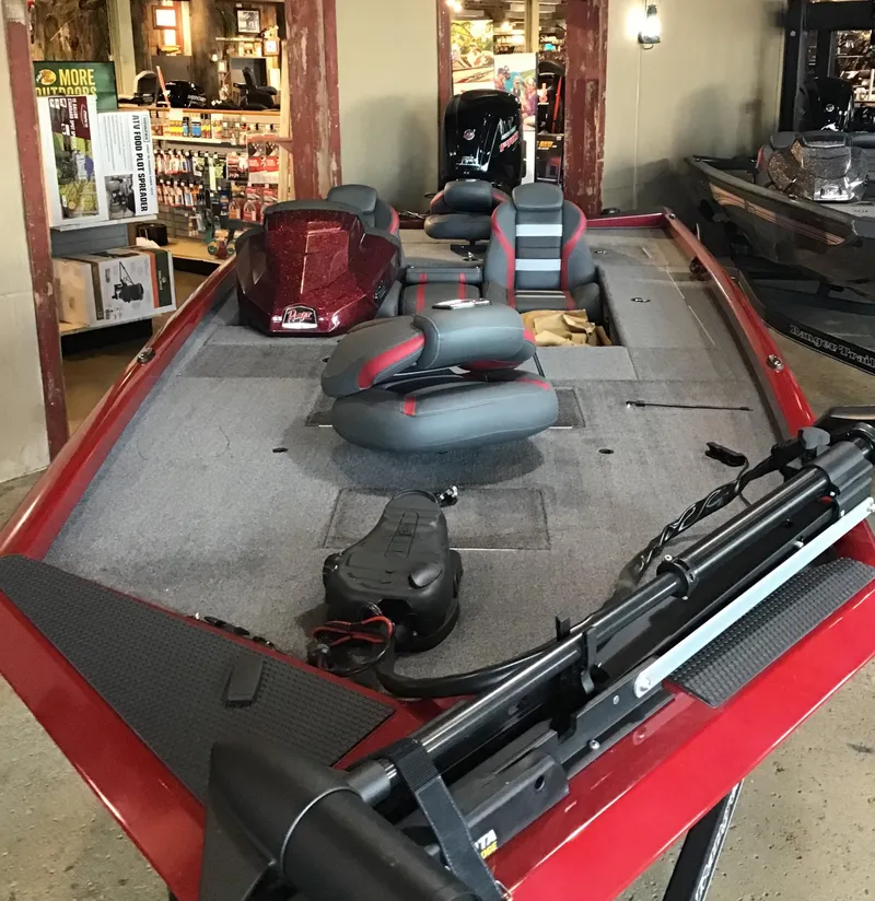 Slide: The Image of 2025 Ranger RT188C fishing boat with red accents and seating, displayed indoors. - 2