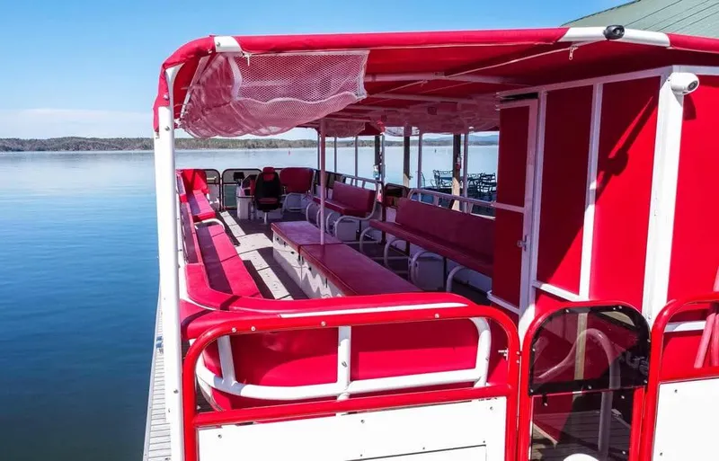 Slide: The Image of 2024 Aloha Pontoon 50' Water Taxi with red seating on a calm lake. - 5