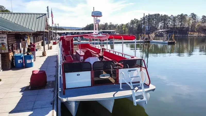 Slide: The Image of 2024 Aloha Pontoon 50' Water Taxi docked at a scenic lakeside marina. - 8
