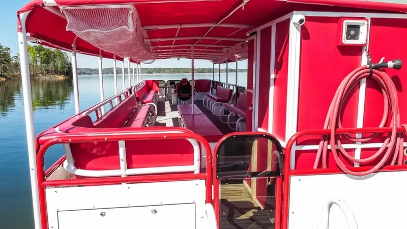 Slide: The Image of 2024 Aloha Pontoon 50' Water Taxi with red seating and canopy on a calm lake. - 9