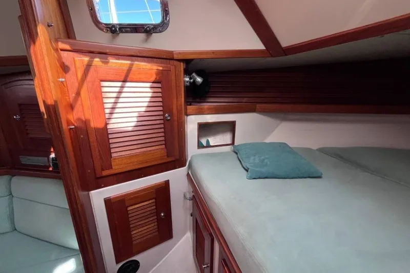 Slide: The Image of Cozy cabin interior of 2002 Pacific Seacraft 40 sailboat with wooden cabinetry and bedding. - 26
