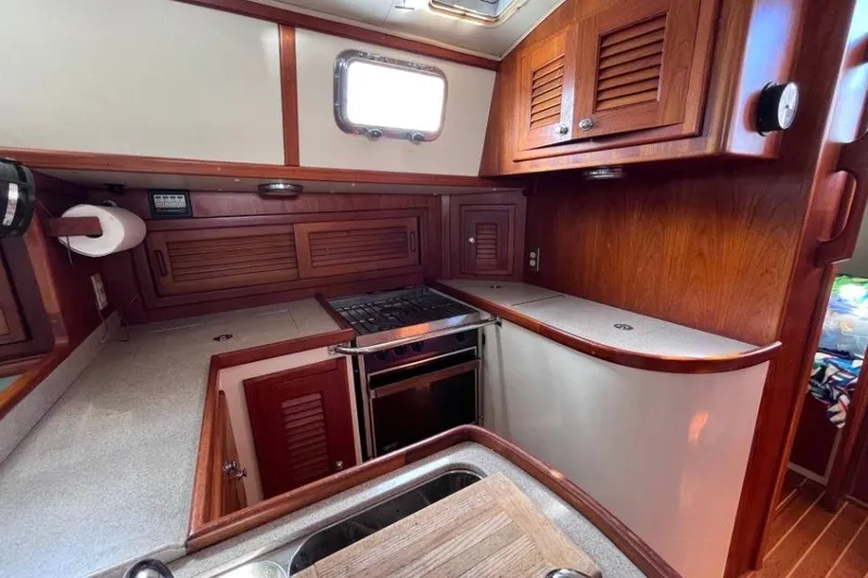 Slide: The Image of Cozy galley kitchen in 2002 Pacific Seacraft 40 sailboat with wooden cabinetry and stove. - 41
