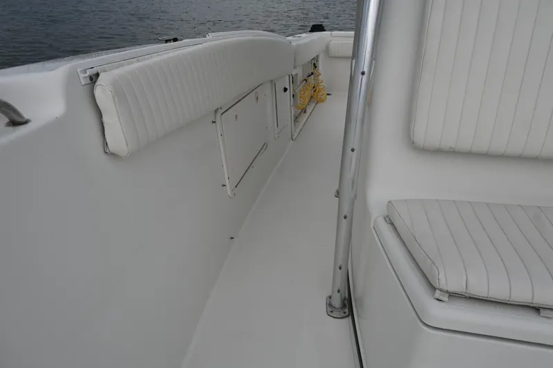 Slide: The Image of 2002 Triton 2895 CC boat interior with white cushioned seating and storage compartments. - 17