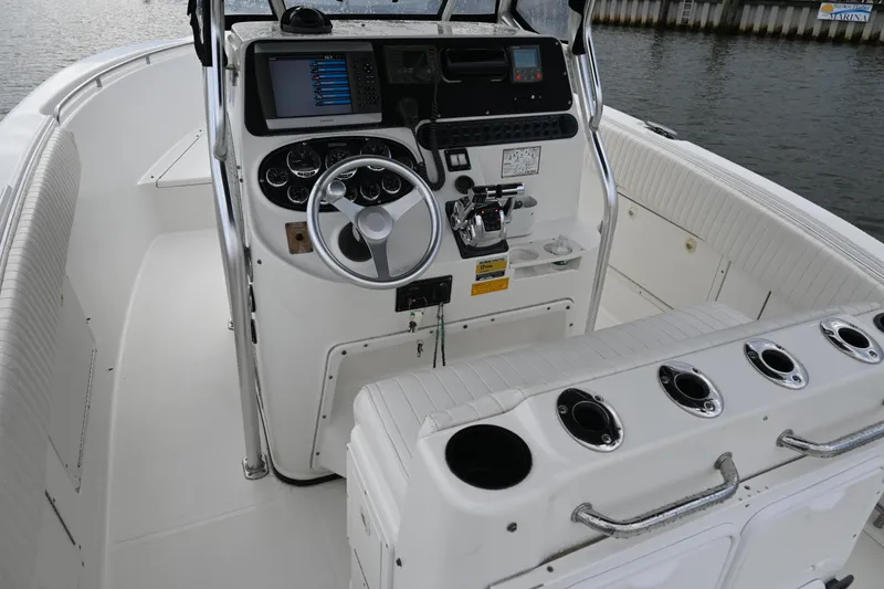 Slide: The Image of 2002 Triton 2895 CC boat cockpit with steering wheel, control panel, and rod holders. - 25