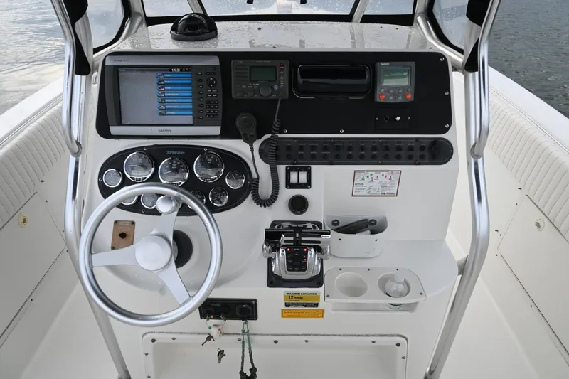 Slide: The Image of 2002 Triton 2895 CC boat dashboard with steering wheel, gauges, and navigation equipment. - 26