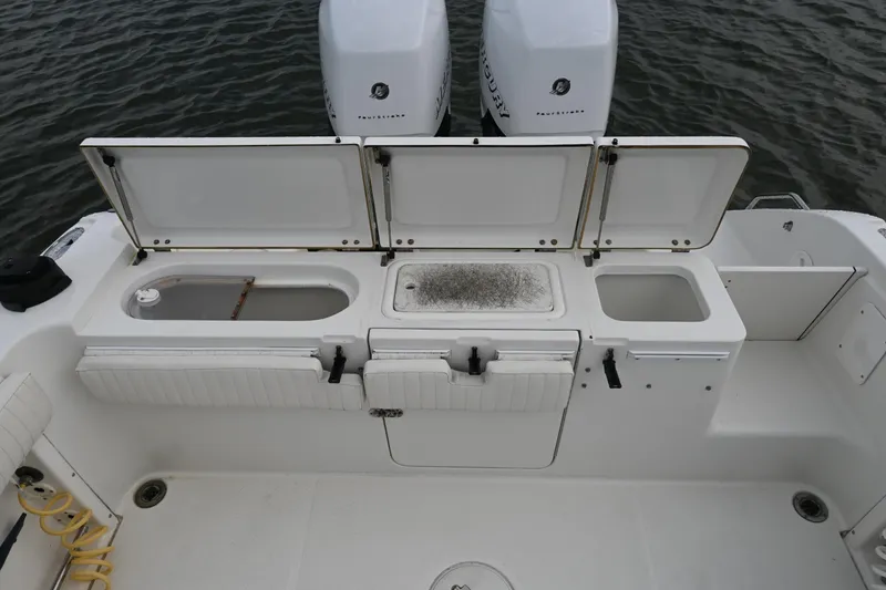 Slide: The Image of 2002 Triton 2895 CC boat deck with open storage compartments and twin outboard motors. - 29