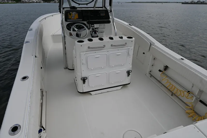 Slide: The Image of 2002 Triton 2895 CC boat interior with steering console, storage, and open deck on water. - 32