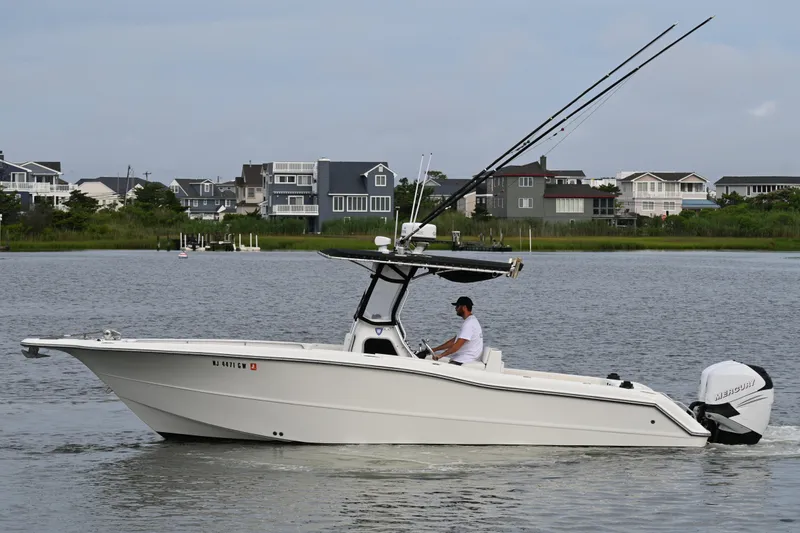 Slide: The Image of 2002 Triton 2895 CC boat on water, with fishing rods and Mercury engine. - 5