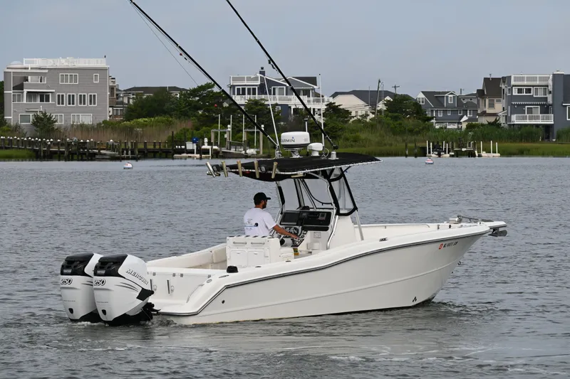 Slide: The Image of 2002 Triton 2895 CC boat with dual engines on a calm waterway near modern homes. - 8