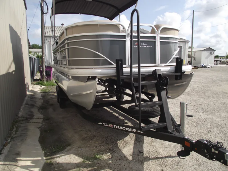 Slide: The Image of 2023 Sun Tracker Party Barge 20 DLX pontoon boat on trailer, parked outdoors. - 2