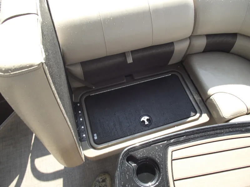 Slide: The Image of 2023 Sun Tracker Party Barge 20 DLX storage compartment with beige seating and cup holder. - 26