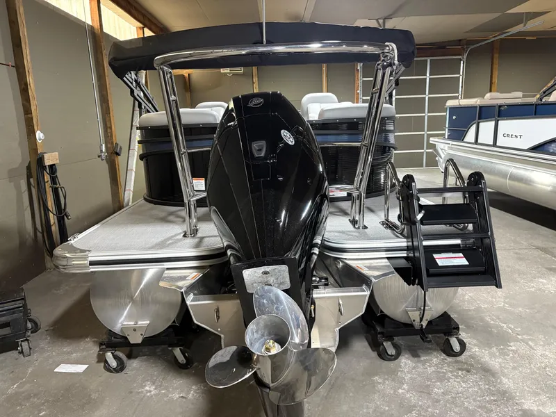 Slide: The Image of 2025 Crest 240 SLC pontoon boat in a garage, rear view with motor and ladder. - 3