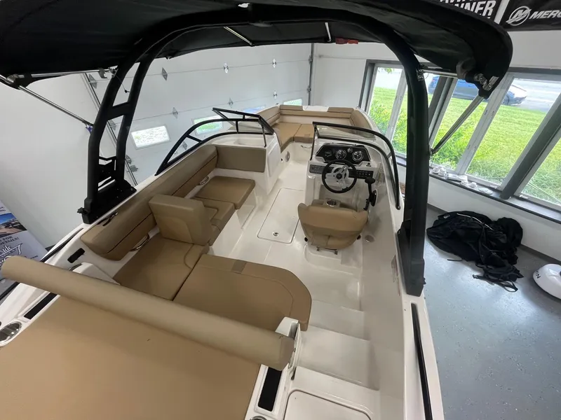 Slide: The Image of 2025 Bayliner D20 boat interior with tan seating and modern helm in a showroom. - 7