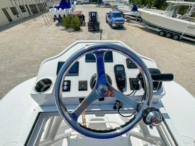 Slide: The Image of 2024 Caymas 28 HB boat helm with steering wheel and controls, parked in a marina. - 22