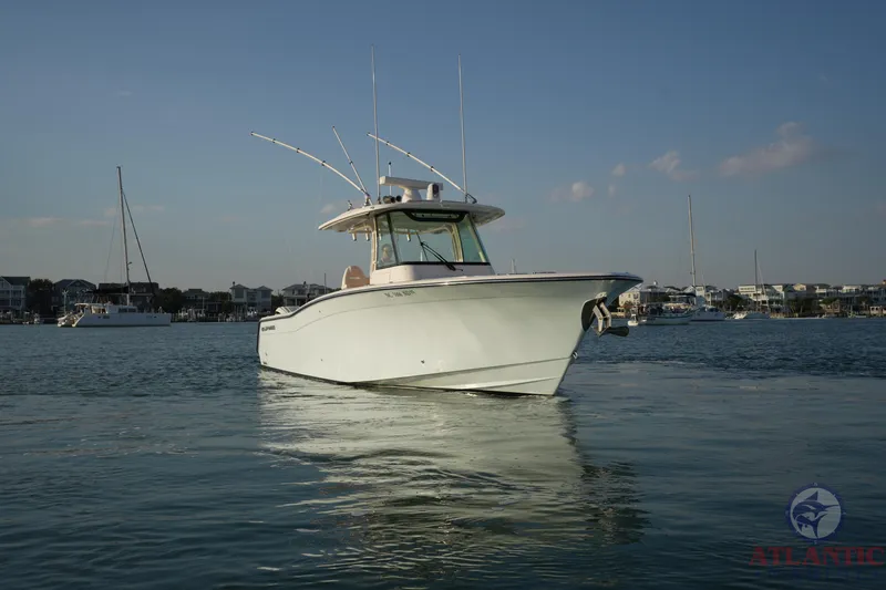Slide: The Image of 2024 Grady-White Canyon 336 boat on calm water, with a marina backdrop. - 12