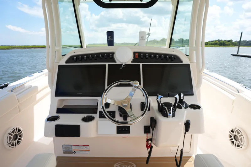 Slide: The Image of 2024 Grady-White Canyon 336 helm with dual screens and steering wheel, overlooking serene waters. - 22