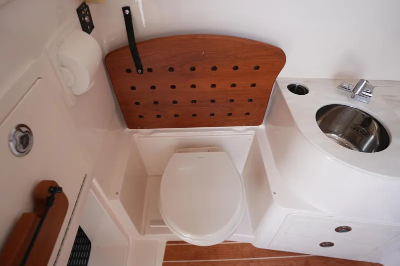 Slide: The Image of 2024 Grady-White Canyon 336 boat bathroom with toilet, sink, and wooden accents. - 36