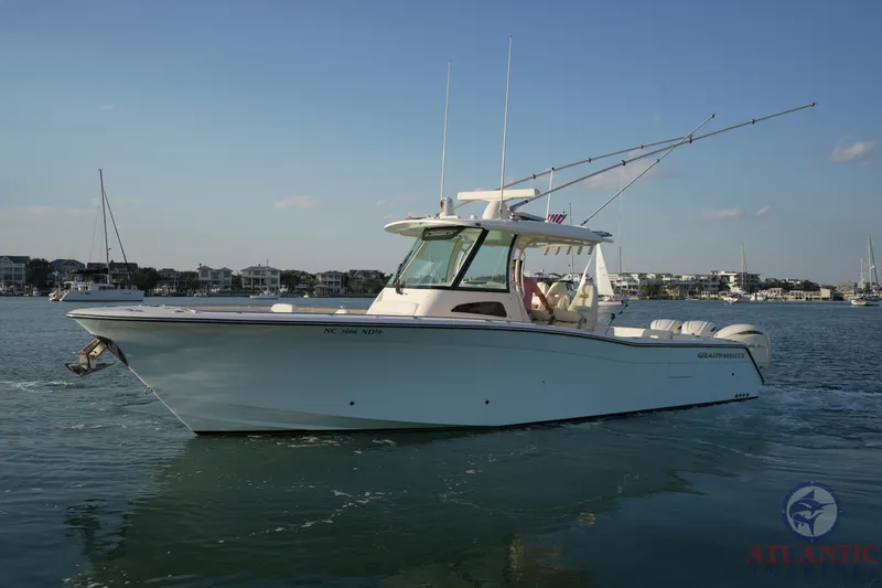 Slide: The Image of 2024 Grady-White Canyon 336 boat cruising on calm waters near a coastal town. - 8