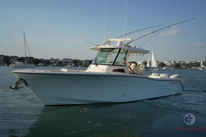 Slide: The Image of 2024 Grady-White Canyon 336 boat on calm water, with fishing rods and coastal background. - 9