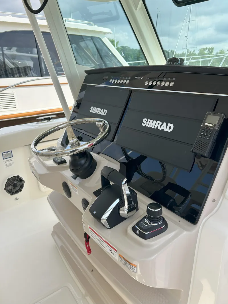 Slide: The Image of 2025 Boston Whaler 360 Outrage helm with Simrad navigation system and steering wheel. - 13