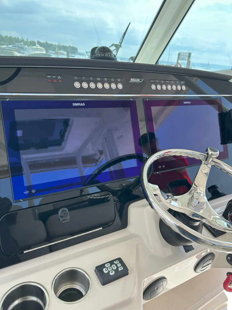 Slide: The Image of 2025 Boston Whaler 360 Outrage helm with dual Simrad displays and steering wheel. - 14