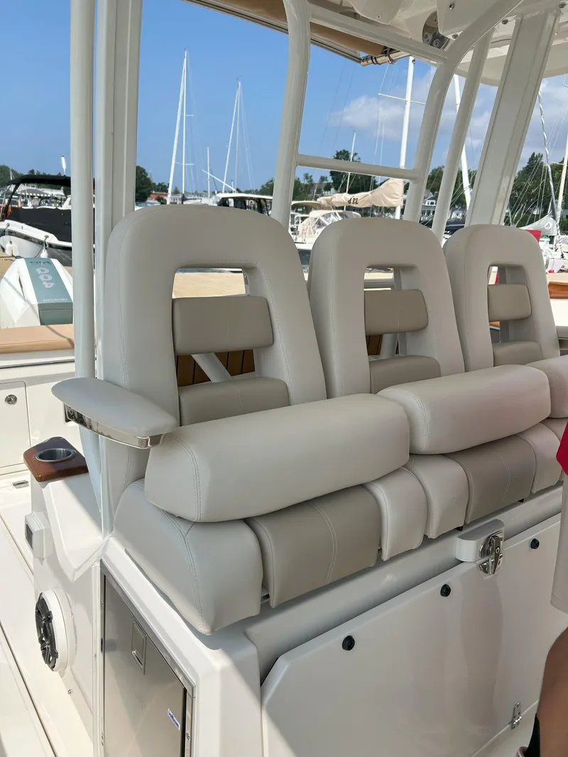 Slide: The Image of 2025 Boston Whaler 360 Outrage boat seats, luxurious white leather, marina background. - 15