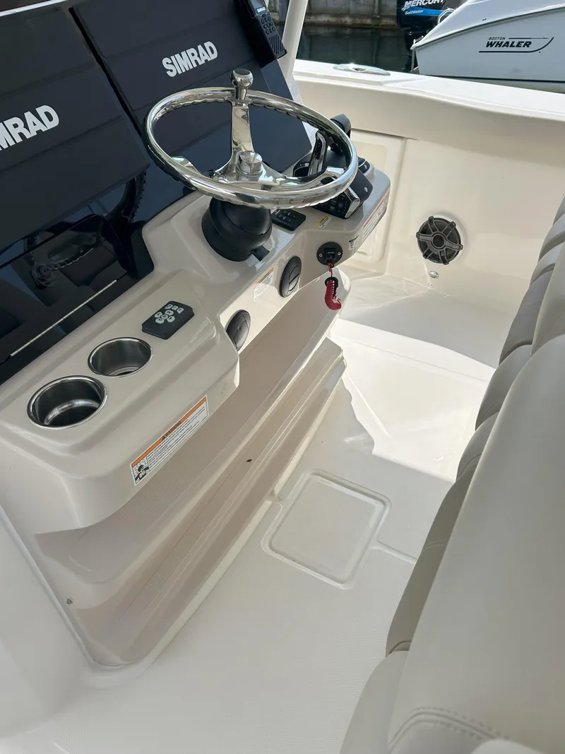 Slide: The Image of 2025 Boston Whaler 360 Outrage helm with Simrad displays and steering wheel. - 17