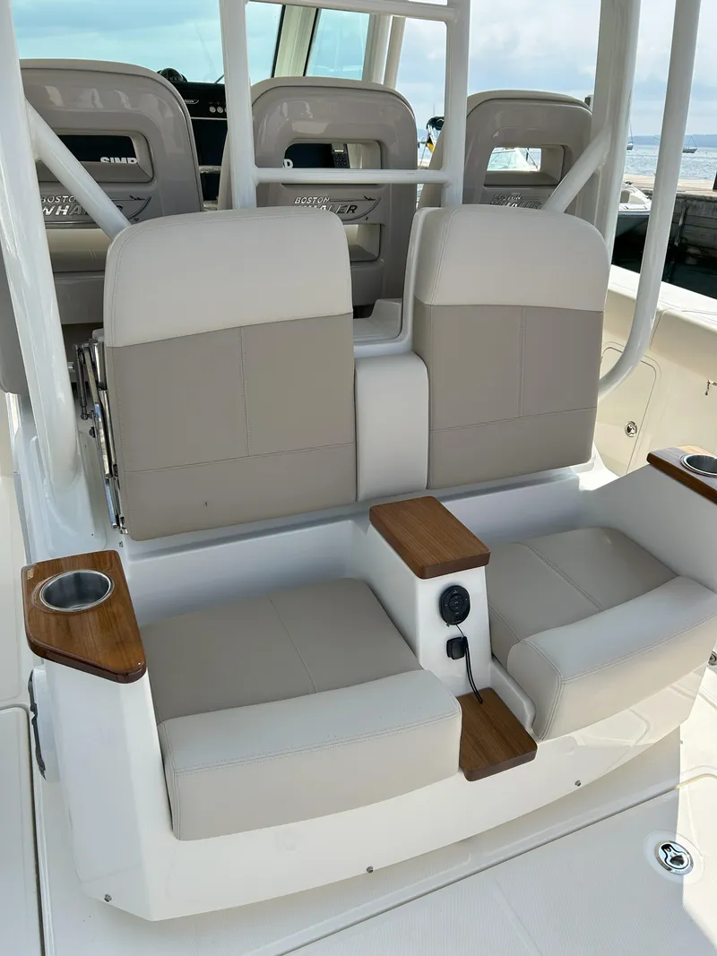 Slide: The Image of 2025 Boston Whaler 360 Outrage boat seating with cup holders and beige cushions. - 18