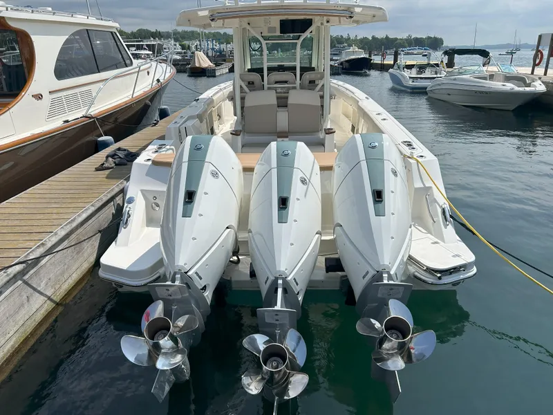 Slide: The Image of 2025 Boston Whaler 360 Outrage with triple outboard engines docked at marina. - 2