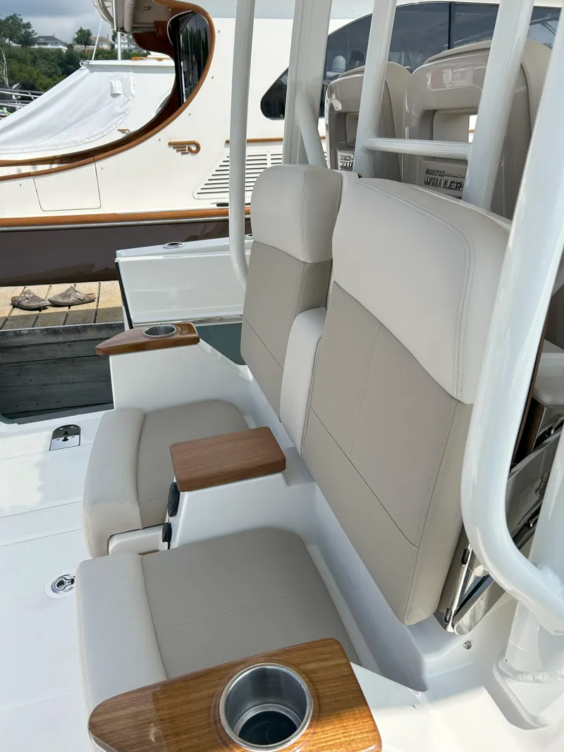 Slide: The Image of 2025 Boston Whaler 360 Outrage boat seats with cup holders and wooden armrests. - 20