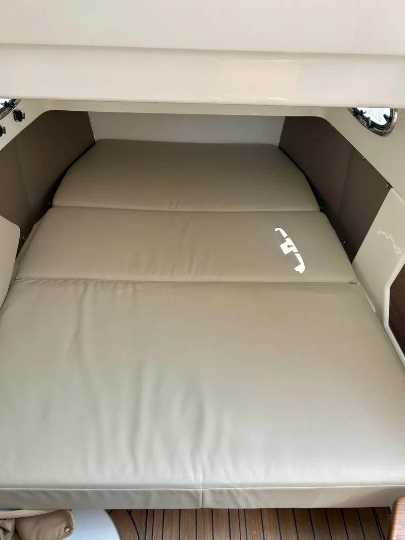 Slide: The Image of 2025 Boston Whaler 360 Outrage cabin interior with beige cushioned bed. - 23