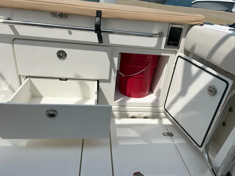 Slide: The Image of 2025 Boston Whaler 360 Outrage storage area with open drawers and red bucket. - 28