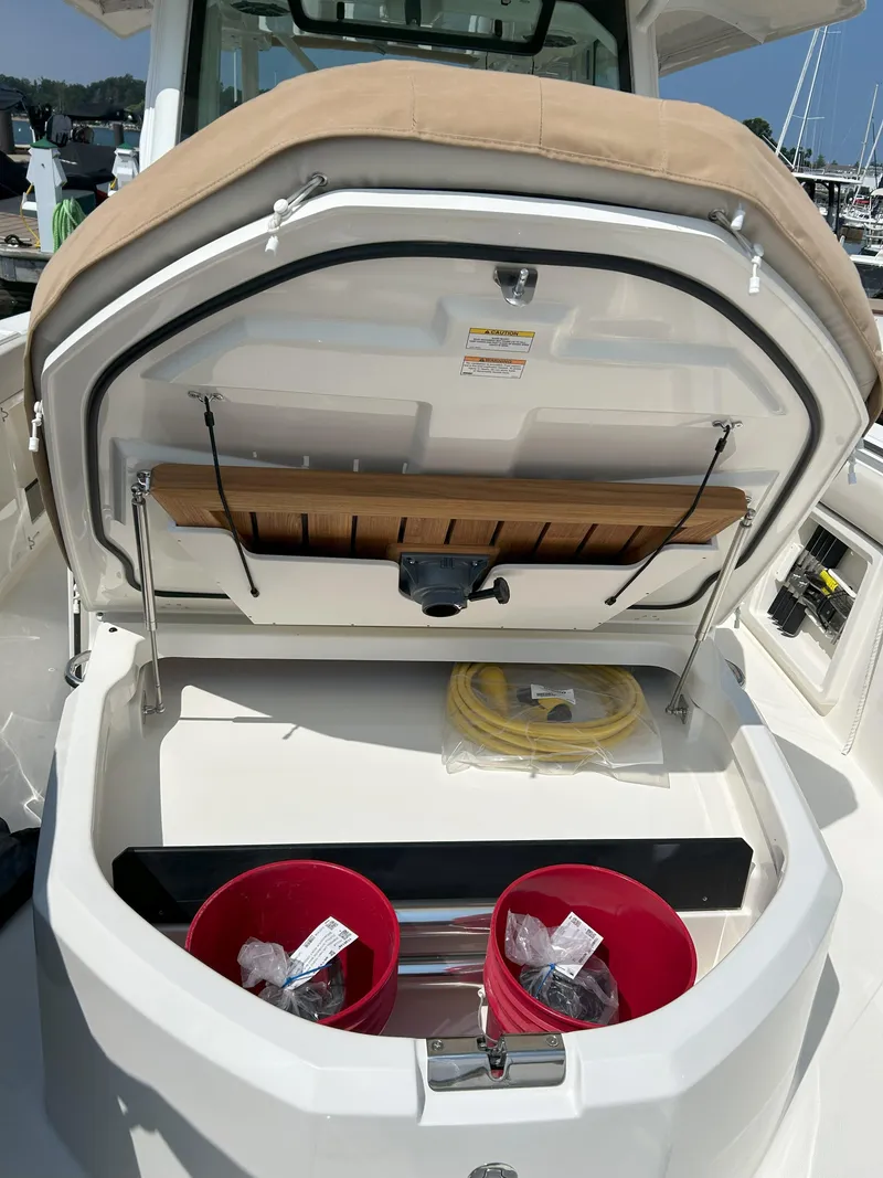 Slide: The Image of 2025 Boston Whaler 360 Outrage storage compartment with buckets and coiled yellow rope. - 34