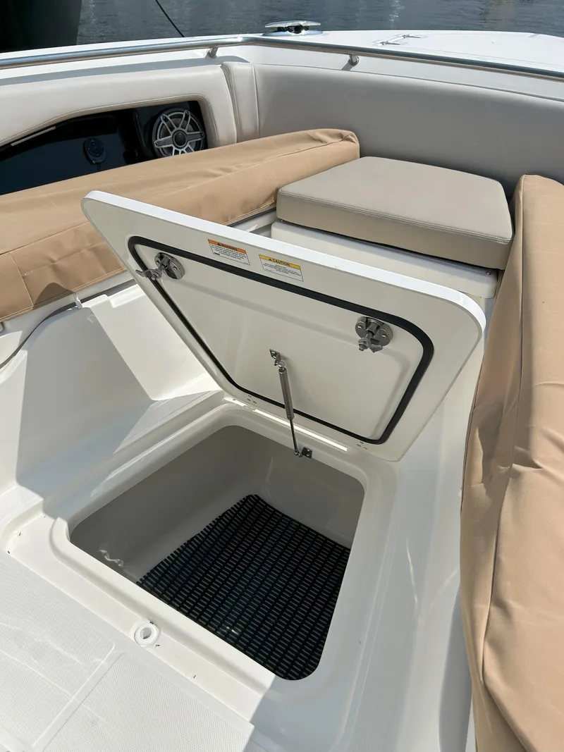 Slide: The Image of 2025 Boston Whaler 360 Outrage storage compartment with cushioned seating and open hatch. - 35