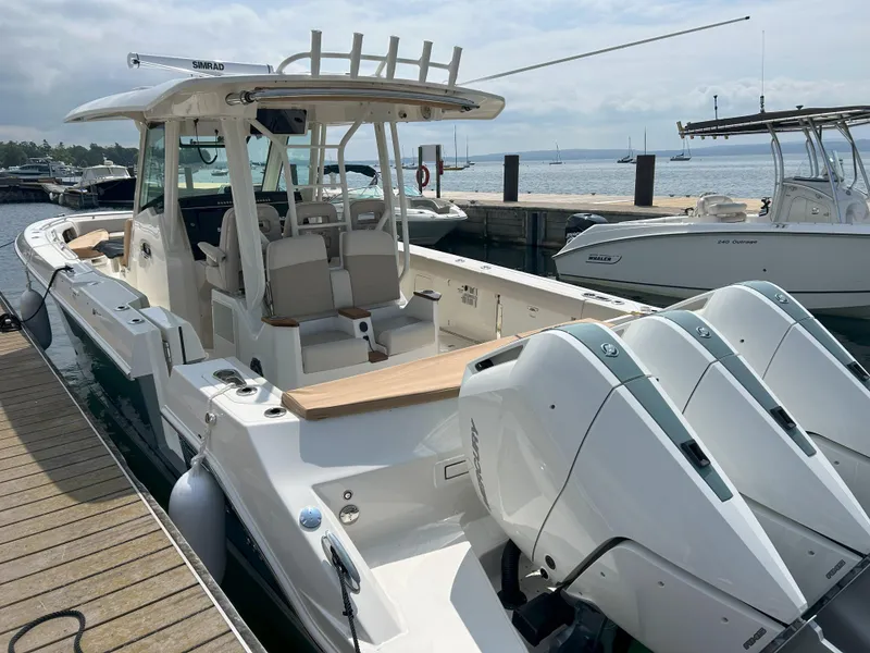 Slide: The Image of 2025 Boston Whaler 360 Outrage boat docked, featuring triple outboard engines and spacious seating. - 4