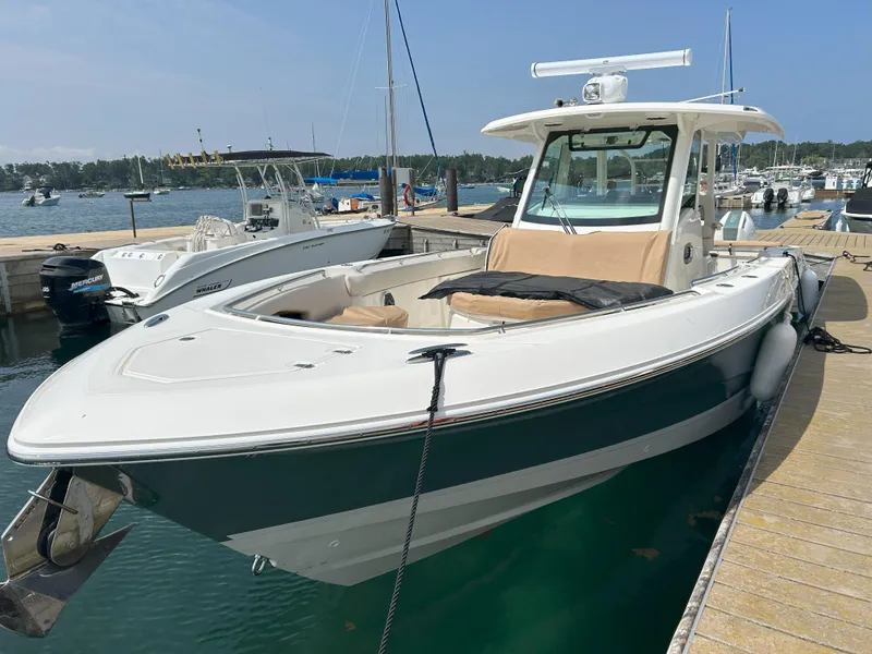 Slide: The Image of 2025 Boston Whaler 360 Outrage docked at marina, showcasing sleek design and spacious deck. - 5