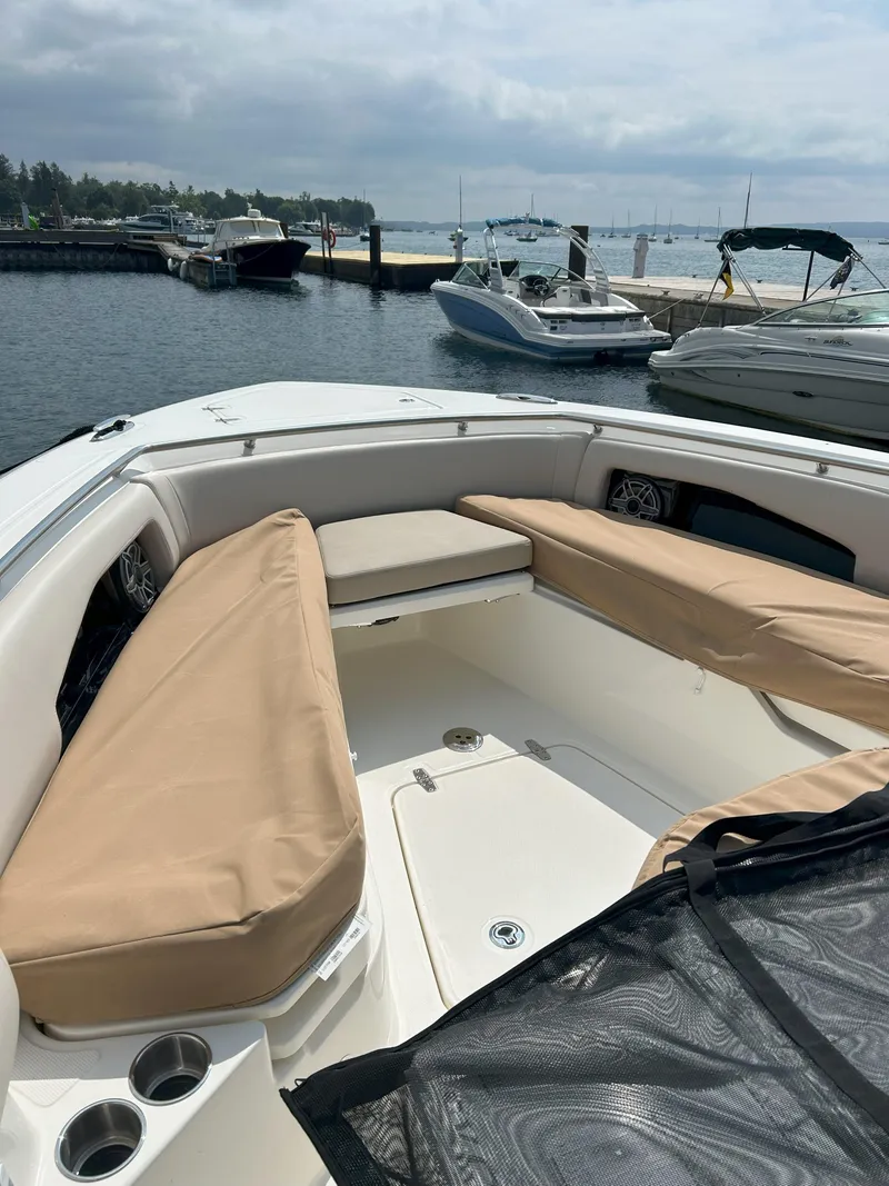 Slide: The Image of 2025 Boston Whaler 360 Outrage boat interior with beige seating at a marina. - 7
