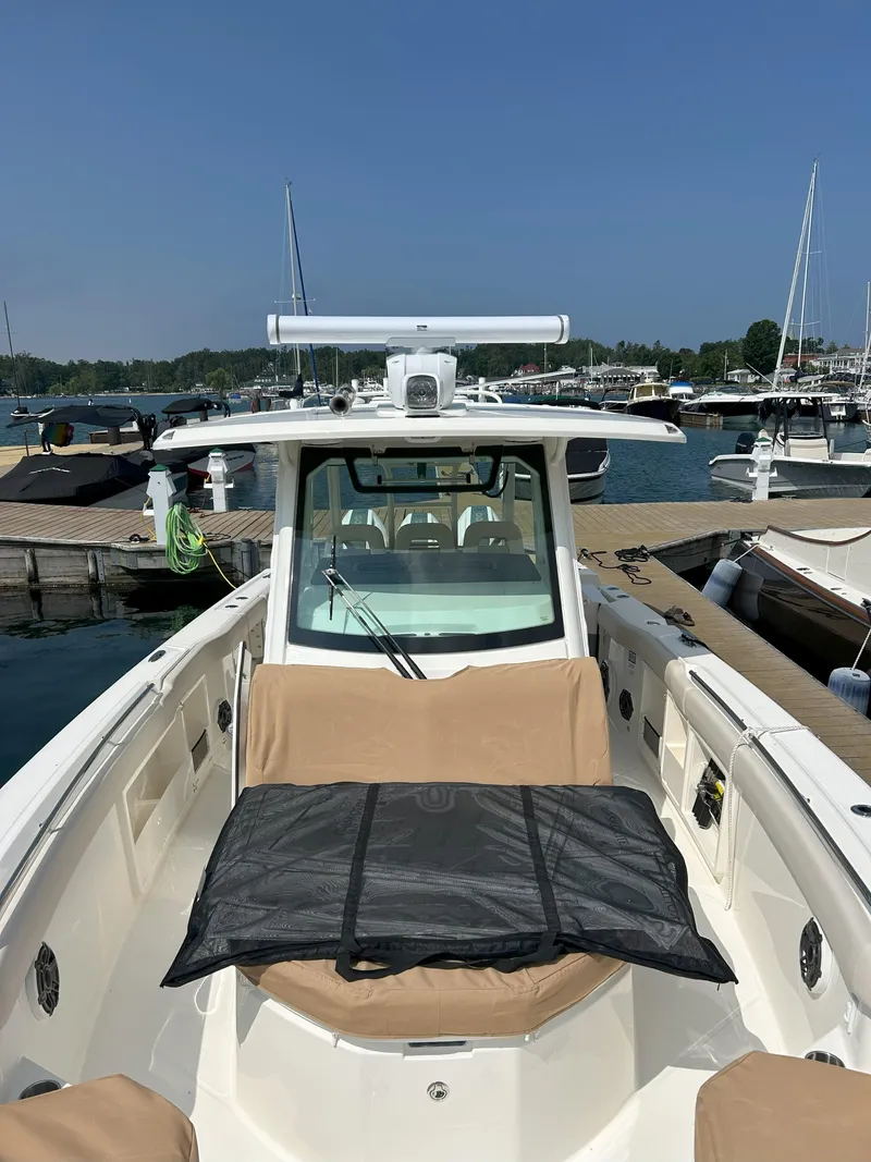 Slide: The Image of 2025 Boston Whaler 360 Outrage boat docked at marina, featuring spacious deck and seating. - 8