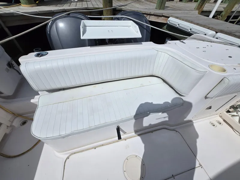 Slide: The Image of 2003 Grady-White Marlin 300 boat seating area with white upholstery and dock background. - 29