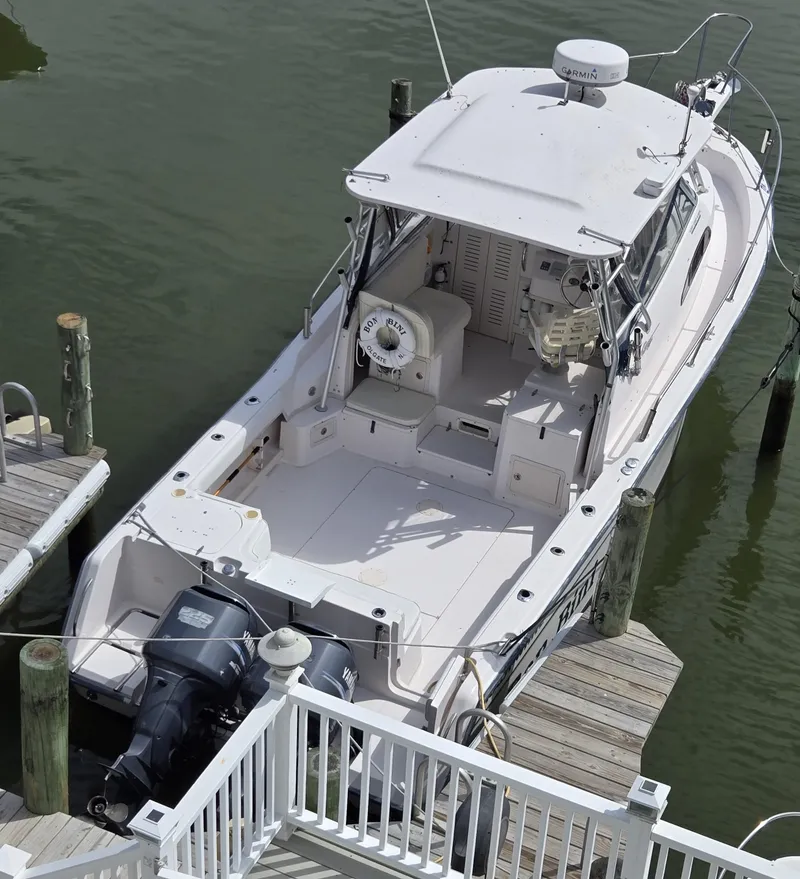 Slide: The Image of 2003 Grady-White Marlin 300 boat docked, featuring spacious deck and twin outboard motors. - 3