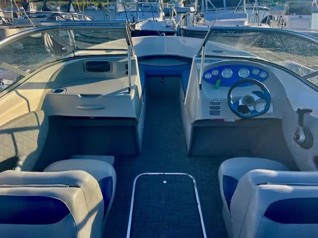 Slide: The Image of 2006 Bayliner 215 Classic boat interior with steering wheel and seating, docked at marina. - 4