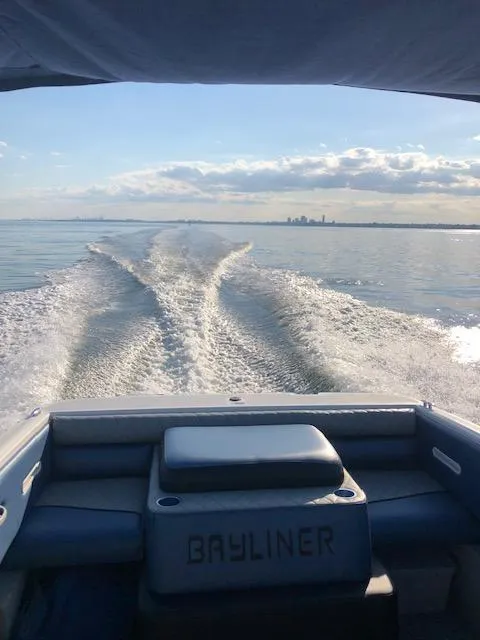 Slide: The Image of 2006 Bayliner 215 Classic boat cruising on open water, leaving a wake behind. - 6