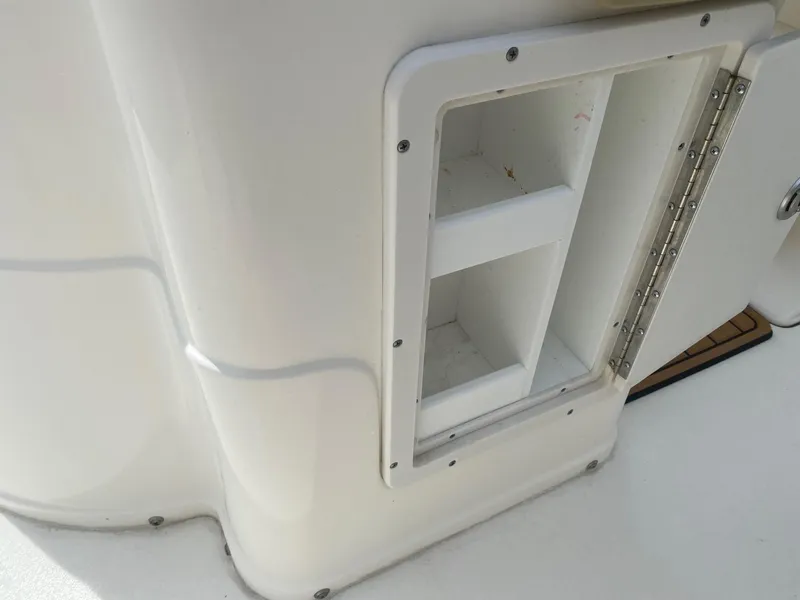 Slide: The Image of 2019 Key West 239 FS boat storage compartment with open door, showcasing interior shelves. - 11