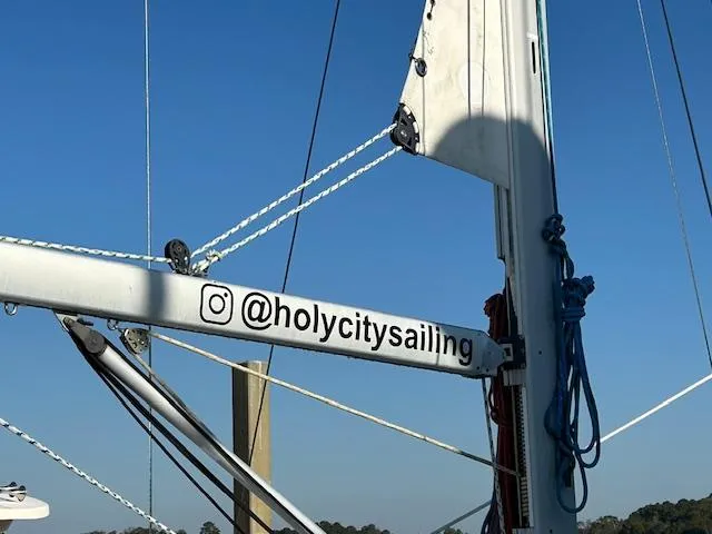 Slide: The Image of Beneteau 373 sailboat mast with "@holycitysailing" Instagram handle, clear blue sky background. - 5