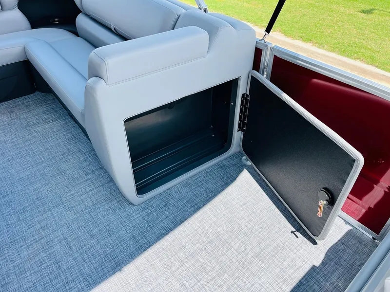 Slide: The Image of 2026 Sun Tracker Party Barge 20 DLX interior with open storage compartment and gray seating. - 30