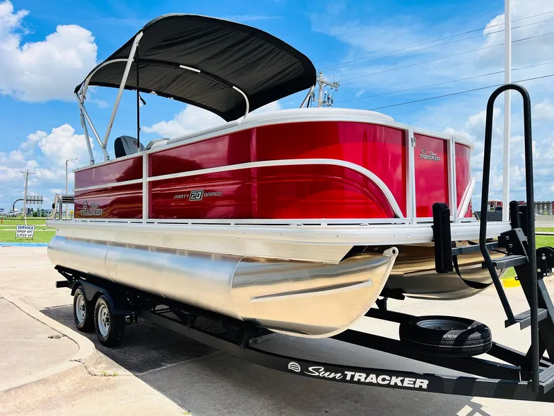 Slide: The Image of 2026 Sun Tracker Party Barge 20 DLX pontoon boat on trailer, red exterior, sunny day. - 4