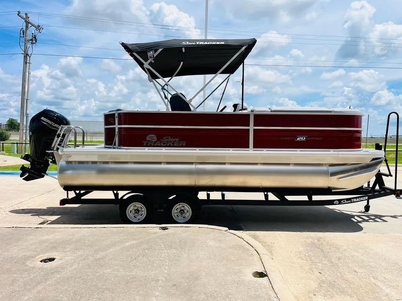 Slide: The Image of 2026 Sun Tracker Party Barge 20 DLX pontoon boat on trailer, under clear sky. - 5