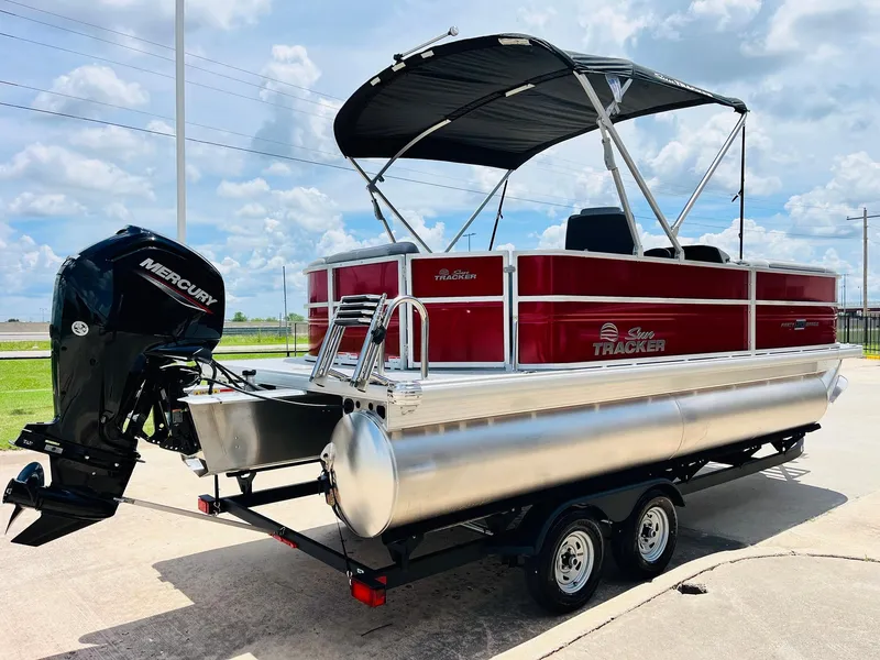 Slide: The Image of 2026 Sun Tracker Party Barge 20 DLX pontoon boat with Mercury outboard motor, parked outdoors. - 6