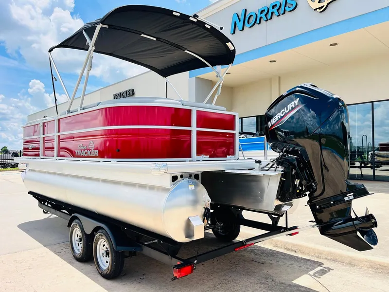 Slide: The Image of 2026 Sun Tracker Party Barge 20 DLX pontoon boat with Mercury engine, parked outside dealership. - 8